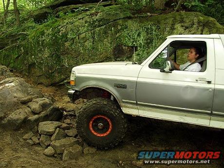 1995 Ford Bronco side view, white and grey, off-roading over rocks