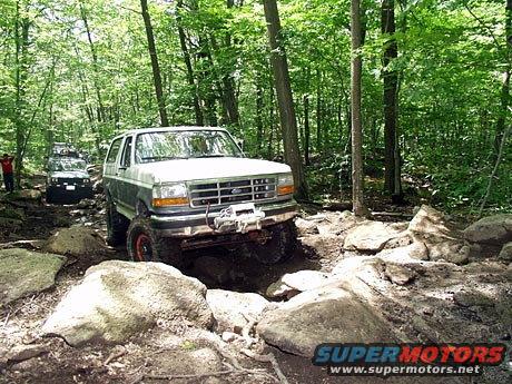 White and grey 1995 Ford Bronco with winch navigating rocky terrain