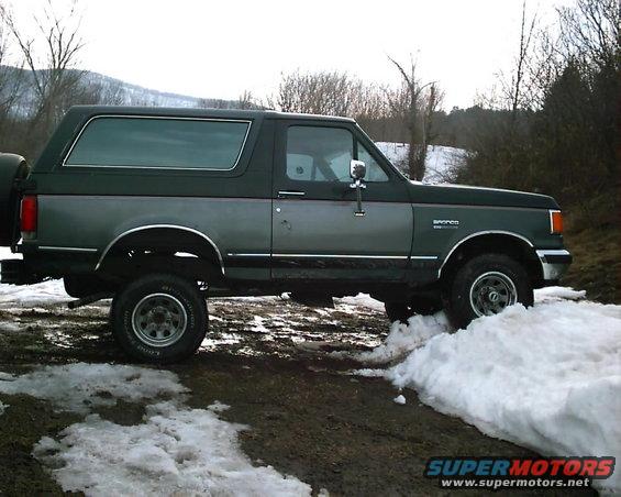 Side view of a 1988 Ford Bronco parked in a snowy, muddy area