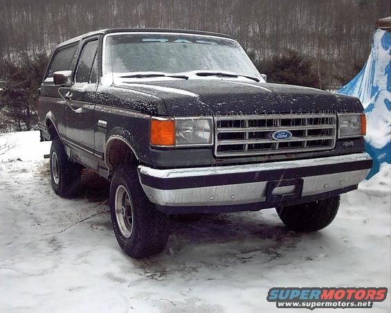 Dark Ford Bronco with snow on it, front 3/4 view, parked in a snowy area