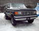 1988 Ford Bronco - A dark Ford Bronco sits in the snow, its grille and headlights visible.