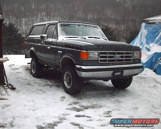Dark SUV with white roof in snow, front 3/4 view. Visible grille and headlights