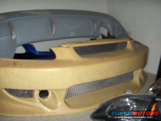 Unpainted aftermarket car bumper and a headlight assembly