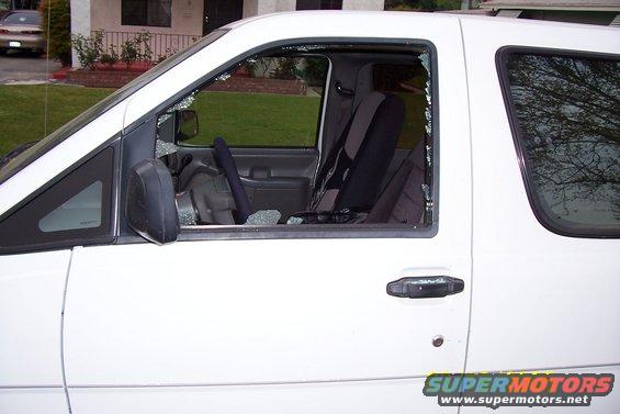 White van with broken driver's side window and shattered glass on the interior
