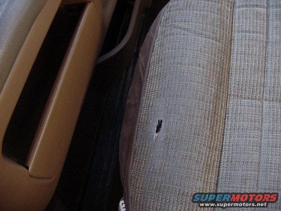 Torn fabric on a car seat, showing a hole in the upholstery