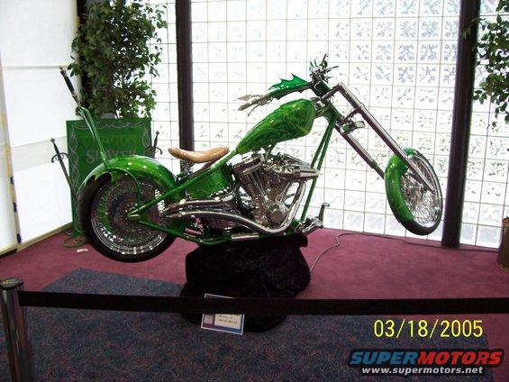 Green custom chopper motorcycle with chrome engine and spoke wheels, displayed indoors