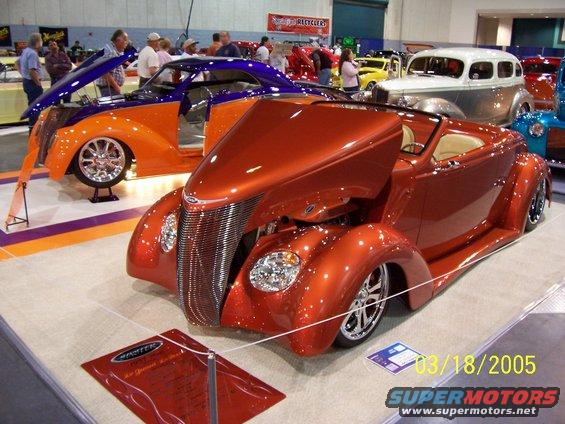 Orange custom hot rod with chrome grille and custom wheels, front view