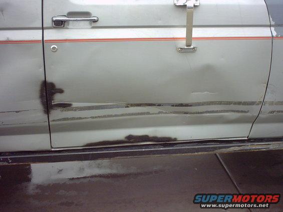 Silver Ford Bronco door with rust damage and a red stripe