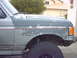 1990 Ford Bronco - The fender and hood of a 1990 Ford Bronco show significant paint wear and a red stripe detail.