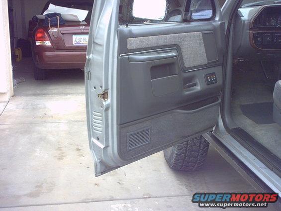 Gray interior door panel of a 1990 Ford Bronco, showing fabric insert and storage compartment