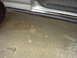 1990 Ford Bronco - The image shows the lower part of a vehicle's side, including the door, running board, and a tire, resting on a stained concrete surface.