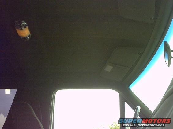 Interior view of vehicle ceiling with sun visors and a hanging object