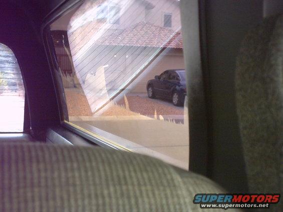 View of a dark sedan parked in a driveway, seen from inside another vehicle