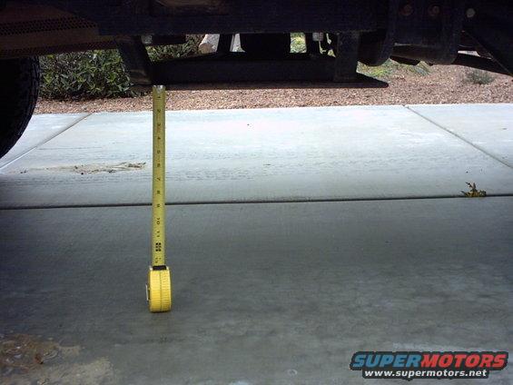 Measuring tape hanging from vehicle frame, showing ground clearance