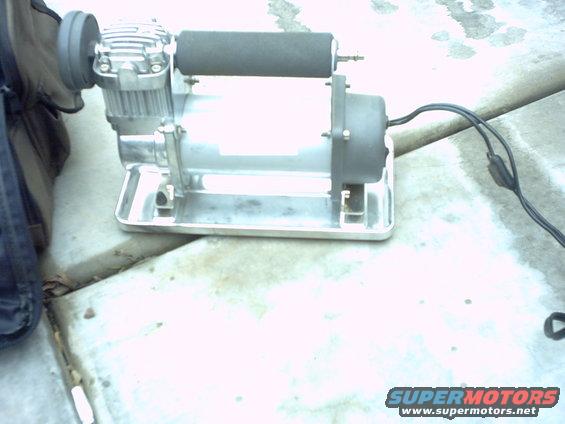 Air compressor on metal base with black hose and grey cylinder