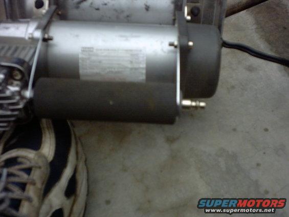 Close-up of an air compressor with a label and a black hose