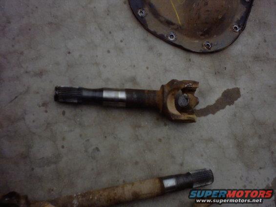 Two rusty driveshaft sections with U-joints on a concrete floor