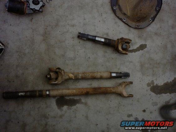 three drive shafts and a differential cover on a concrete floor