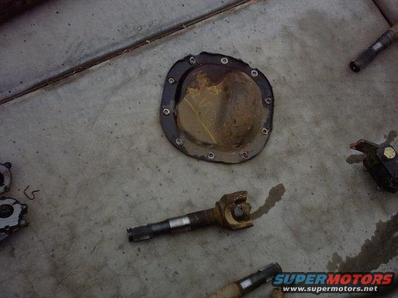 Differential cover and driveshaft parts on concrete floor. Yellow markings on cover