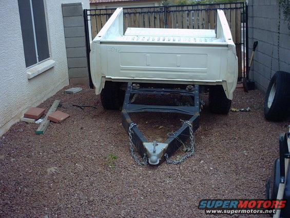 White pickup truck bed mounted on a trailer frame, hitched to a trailer tongue