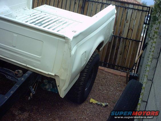 White truck bed with visible rust and damage, seen from the rear