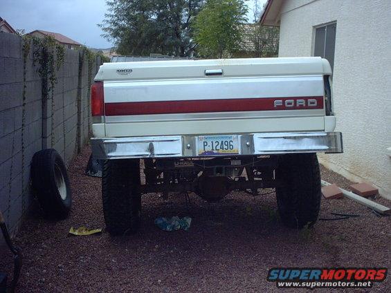 Rear view of a 1990 Ford Bronco with a red stripe on the tailgate and a license plate P-12496