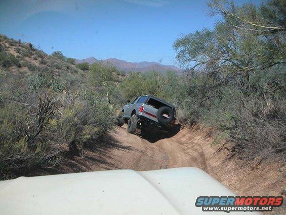 Silver 1990 Ford Bronco on a desert trail, rear spare tire visible