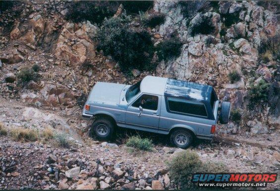 Gray SUV with a removable top on a rocky trail. Visible text: SUPERMOTORS