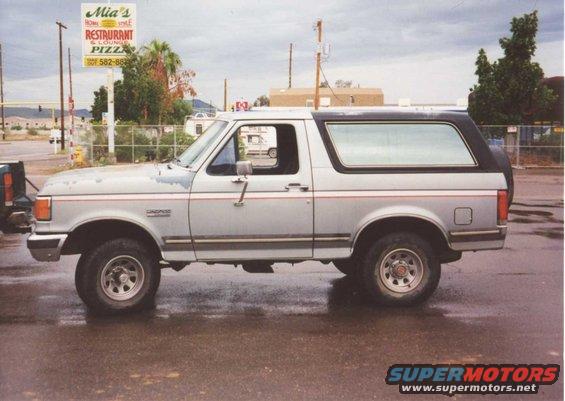 1990 Ford Bronco parked on wet street, side view