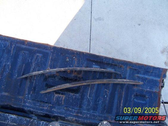 Two leaf springs resting on a blue truck bed