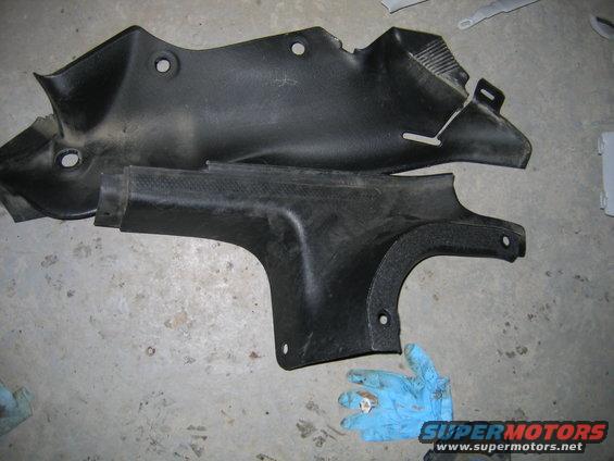 Two black plastic trim pieces on a concrete floor. A gloved hand is visible at the bottom right