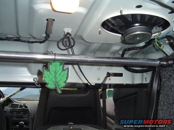 Car interior shot showing a speaker mounted on the ceiling, a metal bar, and a leaf-shaped air freshener
