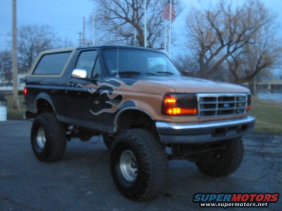 Lifted black and tan Ford Bronco with flame decals, seen from a 3/4 front angle