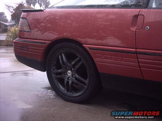 Red car's rear wheel and "TURBO" badge on side panel