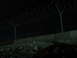 1988 Ford Bronco - Nighttime scene of a fence with barbed wire and a concrete barrier.