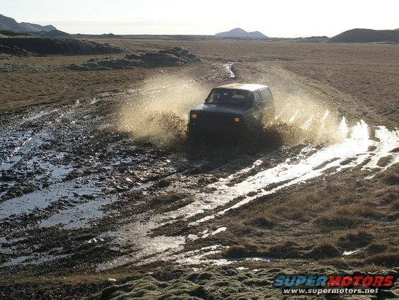 2001 Jeep TJ splashing through a muddy track in a barren landscape