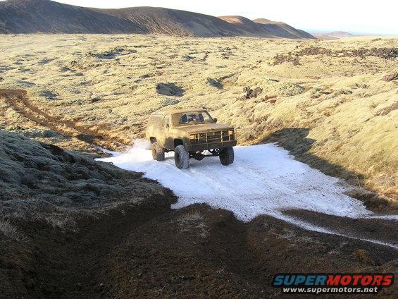 Old Chevy K5 Blazer driving through snow and mud in a barren landscape
