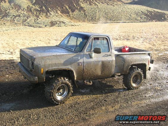 Mud-covered pickup truck with red gas can in bed, off-road tires