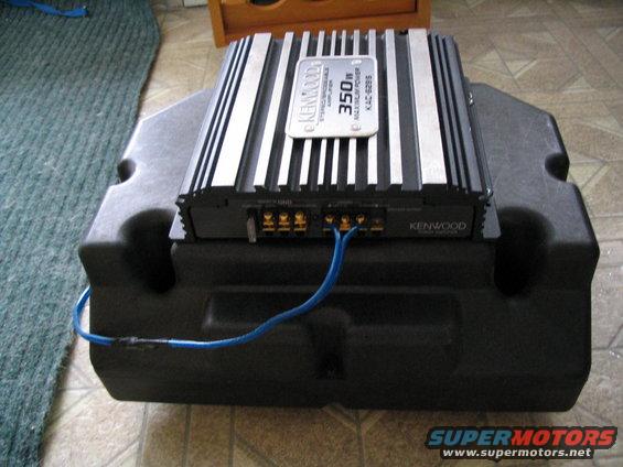 Kenwood amplifier on a black subwoofer enclosure with blue wires