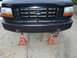 1994 Ford F-150 - The front of a black Ford truck is elevated on jack stands, displaying its grille and a textured bumper.
