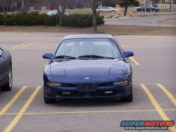 Blue 1993 Ford Probe parked in a lot, front view. Headlights are up