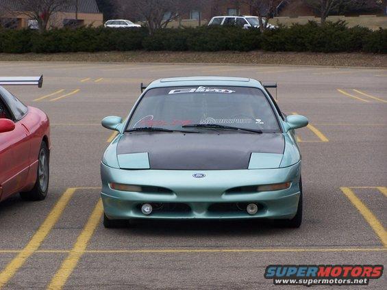 Light blue 1993 Ford Probe with a black hood and a large rear spoiler, parked in a lot