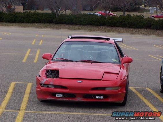 Red 1993 Ford Probe front view with damaged headlight and spoiler