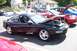 1993 Ford Probe - A black sports coupe with its hood open is parked in a lot with other vehicles.
