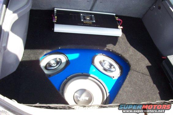 Car trunk with blue subwoofer enclosure and amplifier