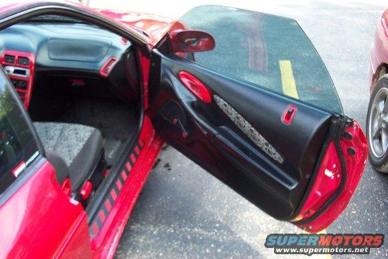 Interior of a red sports car with the driver's door open, showing the dashboard and door panel
