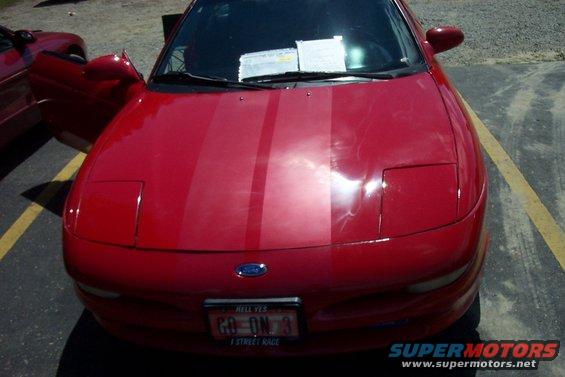 Red 1993 Ford Probe with racing stripes on the hood. Another red car is parked next to it