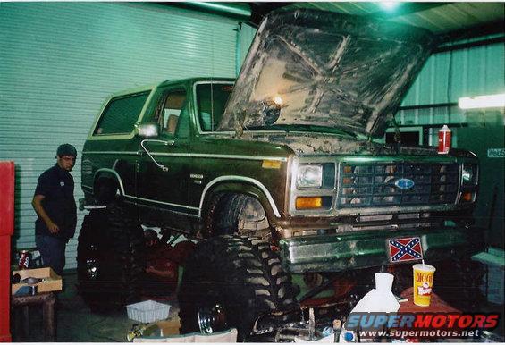 Green 1984 Ford Bronco with hood open, lifted with large tires