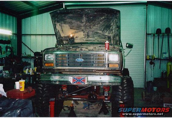 Ford Bronco with hood open, lifted suspension, and large tires in a garage