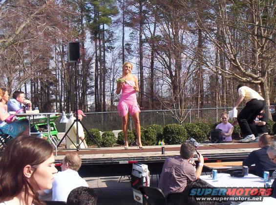 Woman in a short pink dress holding greenery on an outdoor stage